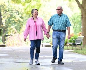 An older couple walks hand-in-hand on 51ƷƵ's campus